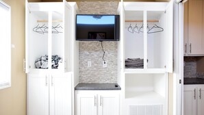 A bedroom with a bed, a TV mounted on the wall, and a wardrobe with hanging space.