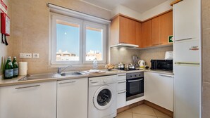 Een moderne keuken met een wasmachine, oven, magnetron en een koelkast.