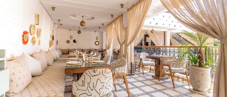 A dining area with a long table set for a meal, surrounded by patterned chairs and a cushioned bench.