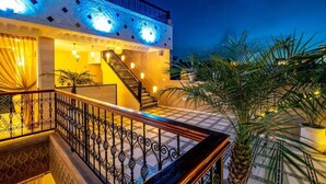 A hotel with a staircase leading to a balcony, a pool area, and palm trees. -  Riad Hamdane Rooftop & SPA  (Marrakech)