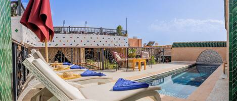 A poolside area with lounge chairs, a table, and a decorative arch.