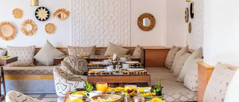 Una sala de estar acogedora con un conjunto de sofá, una mesa de centro con alimentos para el desayuno y decoración en la pared.