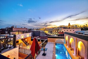 Una piscina al aire libre, sombrillas, sillones reclinables de piscina
