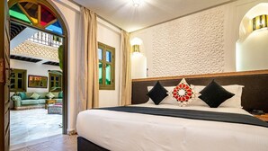 A hotel room with a large bed, a decorative wall, and a view of the outdoor area. -  Riad Hamdane Rooftop & SPA  (Marrakech)