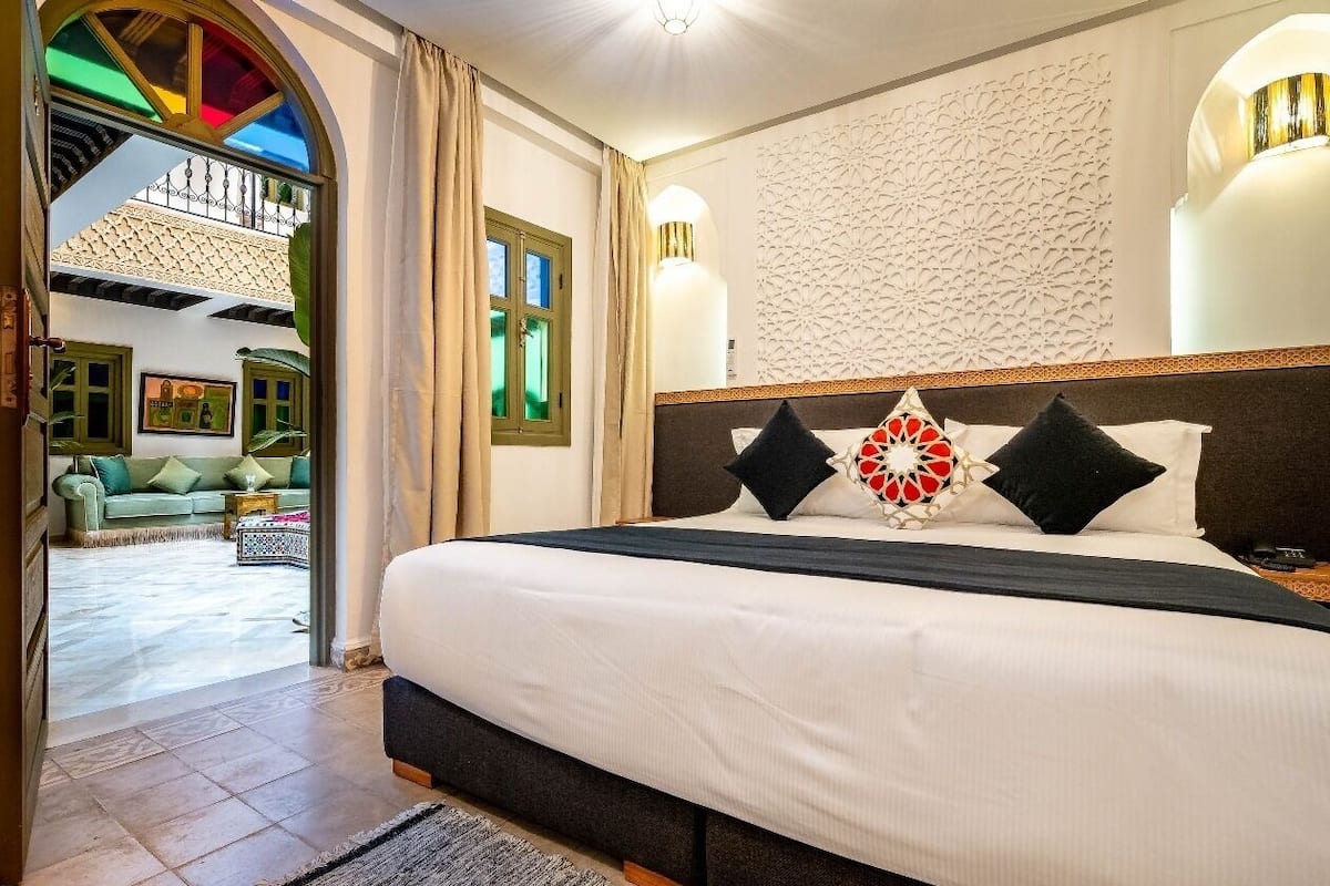 A hotel room with a large bed, a decorative wall, and a view of the outdoor area.