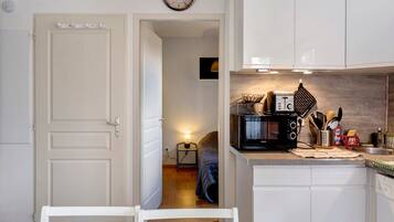 A compact kitchen with white cabinetry, a microwave, and a small table with chairs.