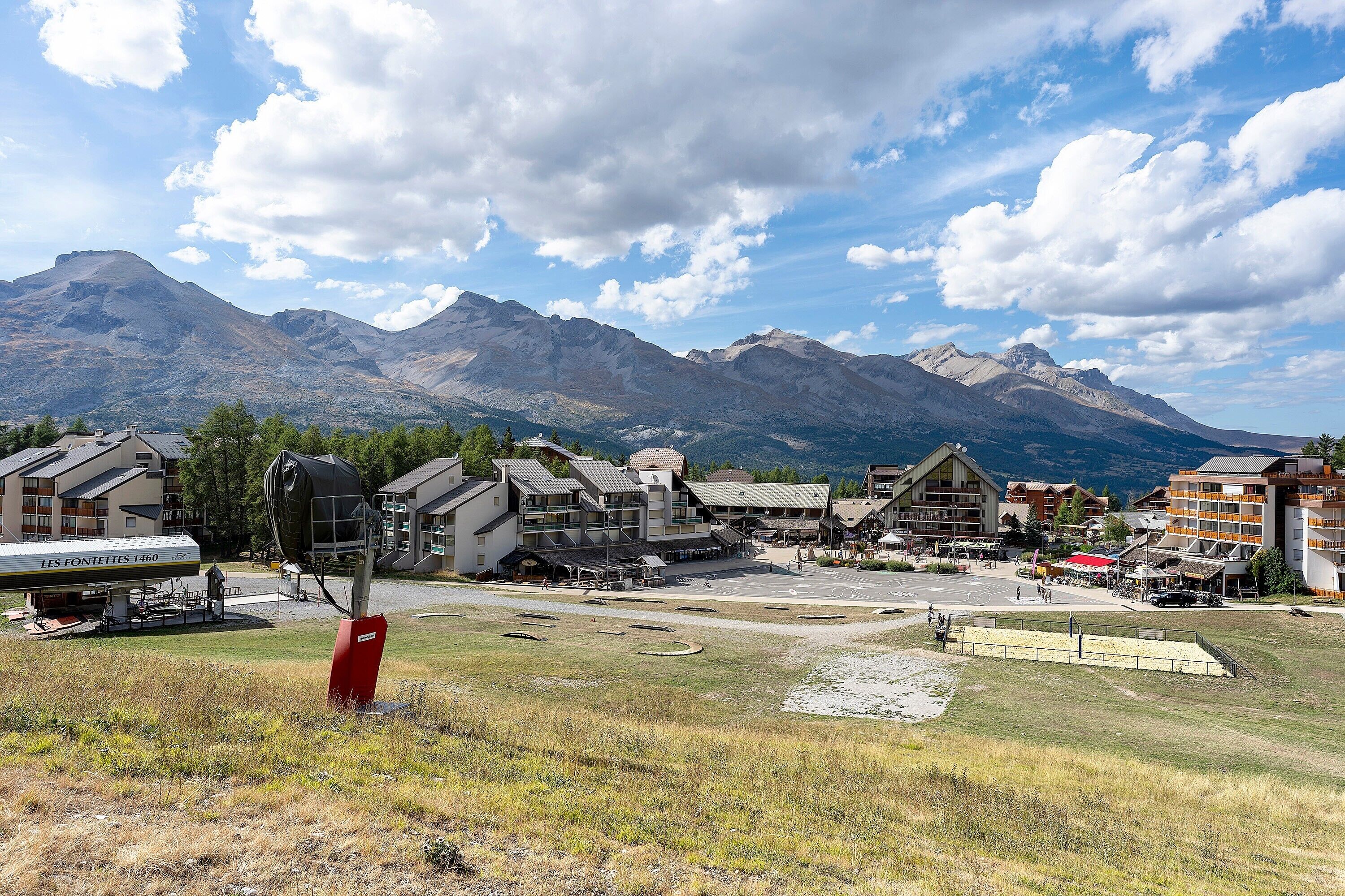 A mountain resort with buildings, a ski lift, and a clear view of the mountains.