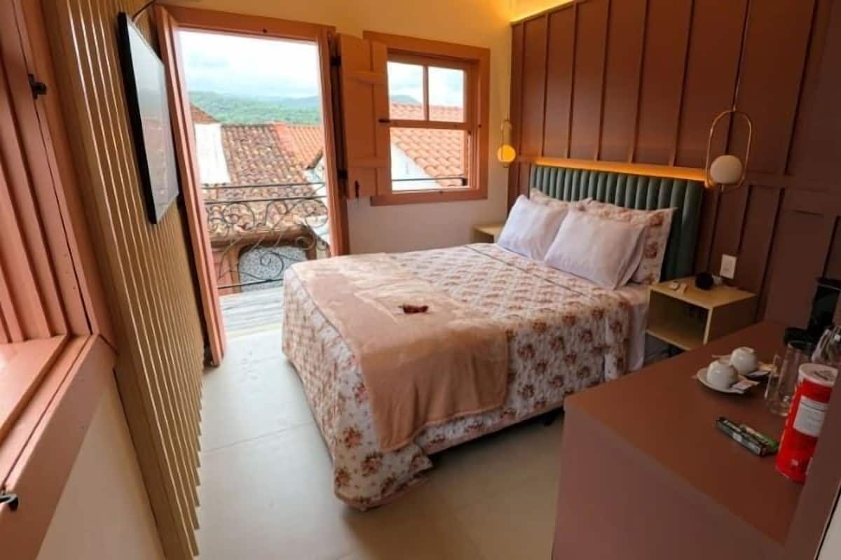 A bedroom with a bed, bedside table, and a view of the outside.