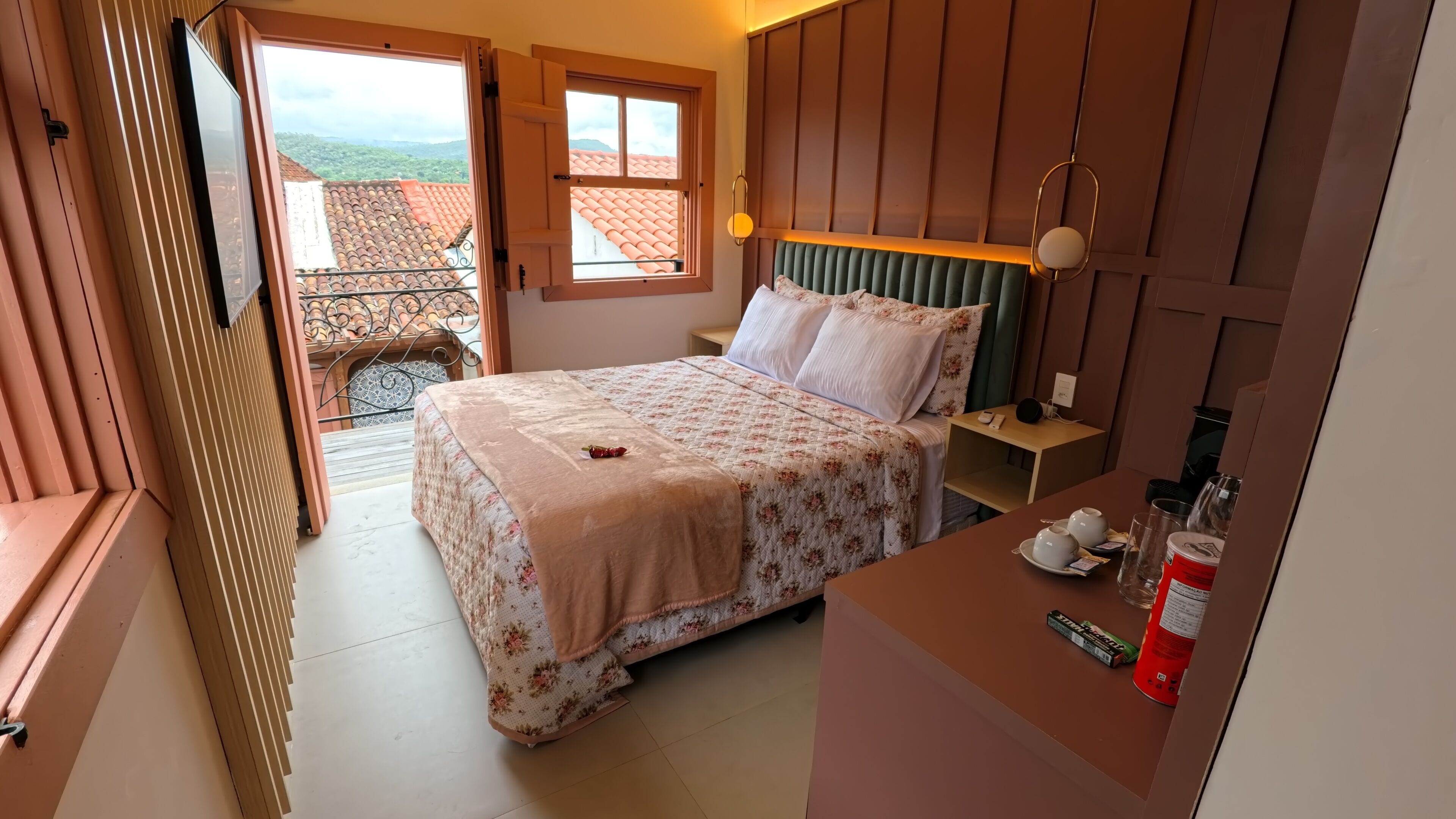A bedroom with a bed, bedside table, and a view of a balcony.