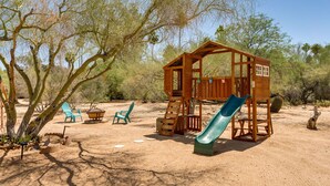 A wooden playhouse with a slide in a desert setting. - Oasis Escape: Quiet & Convenient (Tucson)