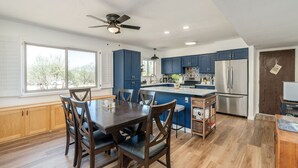 A modern kitchen with blue cabinets, a large island, and a stainless steel refrigerator. - Oasis Escape: Quiet & Convenient (Tucson)