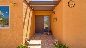 A covered patio with a door, a welcome sign, and a decorative sun emblem. - Oasis Escape: Quiet & Convenient (Tucson)