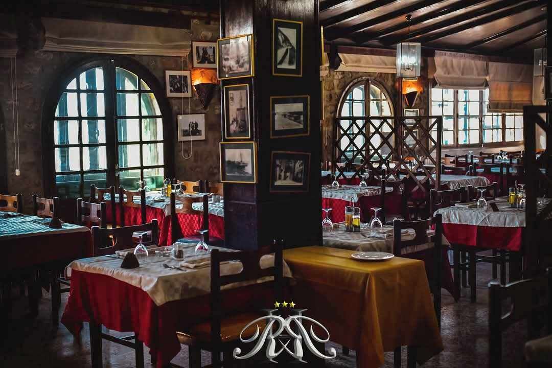 Un restaurante con varias mesas, manteles rojos y cuadros en las paredes.