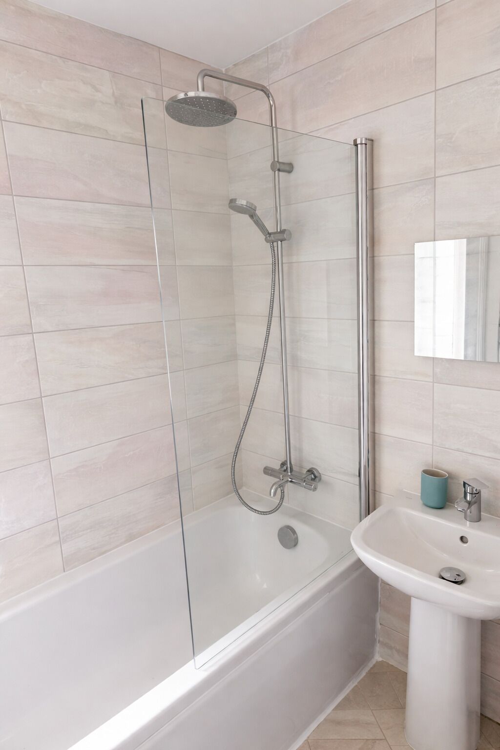 Une salle de bain moderne avec une douche à parois de verre, un lavabo blanc et un miroir.