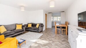 A modern living room with a sofa set, a dining table, and a TV. - Modern 4-bed home near Thirsk| Ideal for Groups, Families & Work Stays (Rainton)
