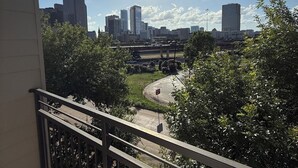 Un balcón con vistas a un paisaje urbano, que incluye edificios altos y una autopista.