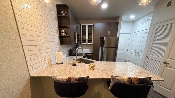 Una cocina moderna con azulejos blancos tipo metro, electrodomésticos de acero inoxidable y encimera de mármol.