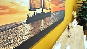 A wall with a large painting of a sailboat on water, a wooden table with vases, and a potted plant. - APARTMENT FREE SHUTTLE (Catania)