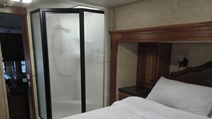 Ett hotellrum med en stor säng, en sänggavel i trä, ett litet skrivbord och en rymlig klädkammare.