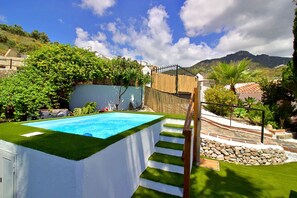 A swimming pool with a white border, a stone staircase, and a view of a mountain.
