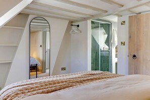 Un dormitorio con cama, espejo, armario y puerta de ducha de vidrio.