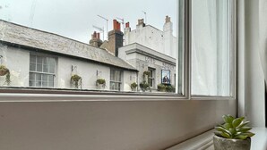 A window with a potted plant on a ledge, overlooking a building with a sign reading 'LORD NELSON'. - Beautiful 2-bed Apartment In The Heart Of The City (Brighton and Hove)