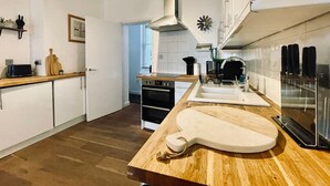 A modern kitchen with wooden countertops, a built-in oven, and a stainless steel range hood. - Beautiful 2-bed Apartment In The Heart Of The City (Brighton and Hove)