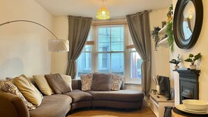 A living room with a sectional sofa, a round rug, a fireplace, and a television. - Beautiful 2-bed Apartment In The Heart Of The City (Brighton and Hove)