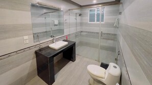 Une salle de bain moderne avec une douche à parois de verre, des toilettes blanches et un meuble-lavabo noir.