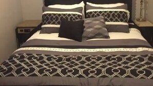 Un letto con copripiumino e cuscini decorati, un comodino e una finestra con persiane.