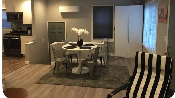 Una cucina compatta con angolo pranzo, una sedia a righe bianche e nere e una pianta in vaso.