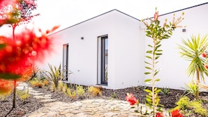 A modern building with a white exterior, a stone pathway, and various plants. - Vale Paraíso Villa - BY SCH (São Martinho do Porto)