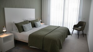 A bedroom with a bed, nightstands, a chair, and a window with sheer curtains. - Vale Paraíso Villa - BY SCH (São Martinho do Porto)