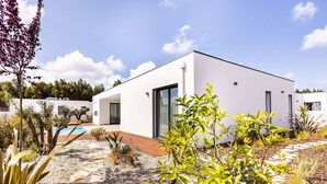 A modern white building with a pool, surrounded by various plants and a clear sky. - Vale Paraíso Villa - BY SCH (São Martinho do Porto)