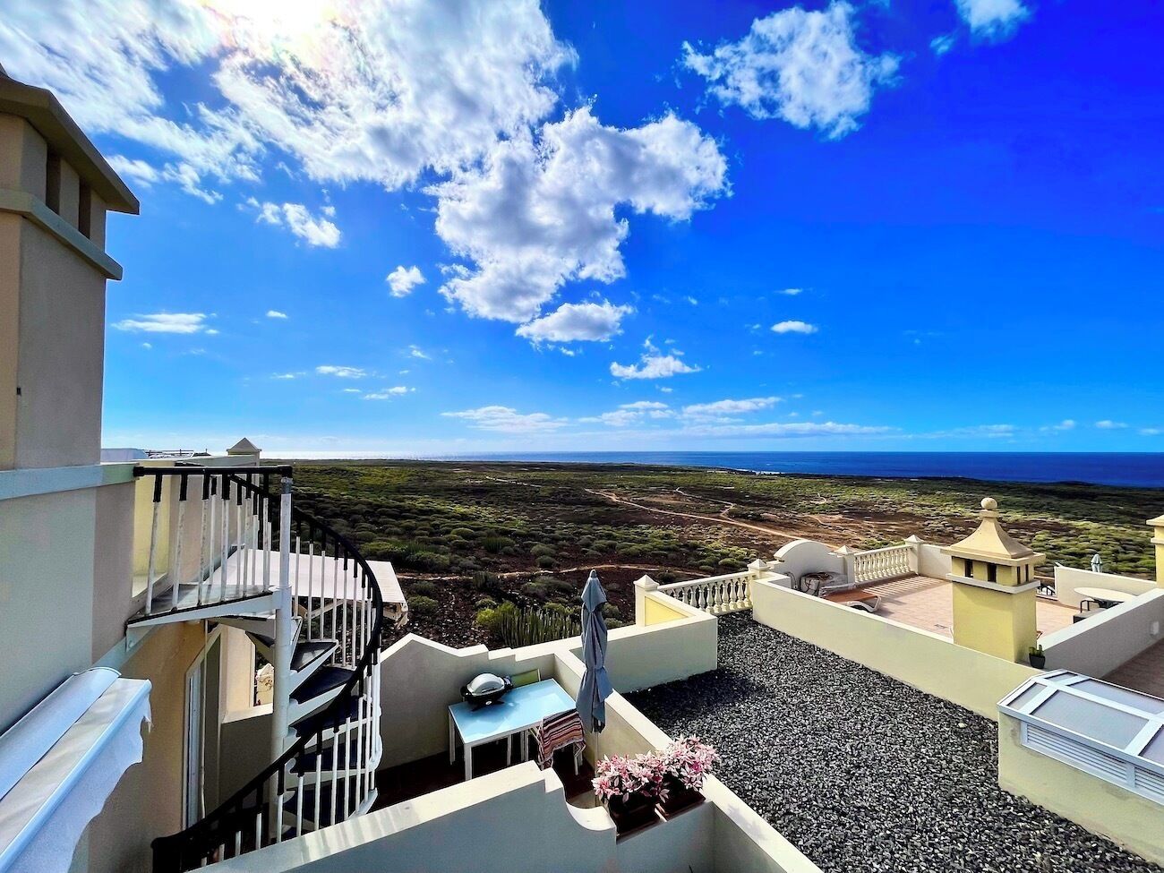 A rooftop terrace with a clear view of the landscape and ocean.