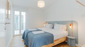 Een slaapkamer met een houten bed, twee nachtkastjes, een hanglamp en uitzicht door een glazen deur.