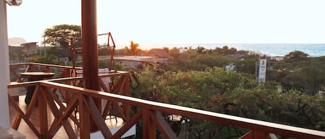 A wooden deck with a view of a coastal area, including a beach and some buildings in the distance.