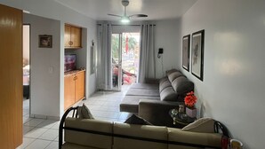 Una sala de estar con un sofá, un televisor y un comedor con una mesa y sillas.