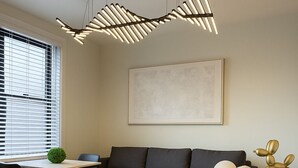 Uma sala de estar moderna com um sofá escuro, uma mesa branca com duas cadeiras, um lustre pendente e uma obra de arte emoldurada na parede.