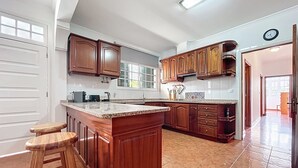 Una cocina con armarios de madera, encimera de granito y una isla grande con taburetes.
