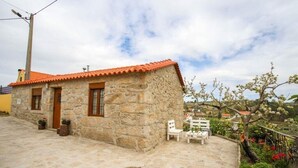 Ein Steinhaus mit rotem Ziegeldach, einem gepflasterten Innenhof und Außenplätzen.