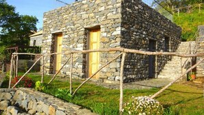 Ein Steinhaus mit zwei Holztüren und einer Treppe, die zu einer höheren Ebene führt.