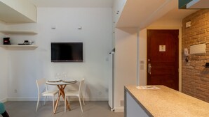 Una cocina moderna con refrigerador integrado, un comedor con mesa y sillas, y un televisor montado en la pared.