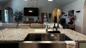 A kitchen with a granite countertop, stainless steel sink, and a ceiling fan.