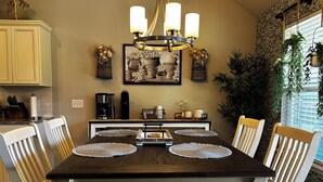A dining area with a dark wooden table, white chairs, and a chandelier.