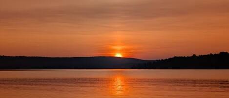 A sunset over a calm lake with a forested shoreline.