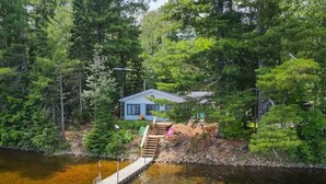 A house with a dock extending into a body of water, surrounded by dense forest. - Enjoy the Autumn colours on the edge of Algonquin park at Gramma's on the Lake (Barry's Bay)