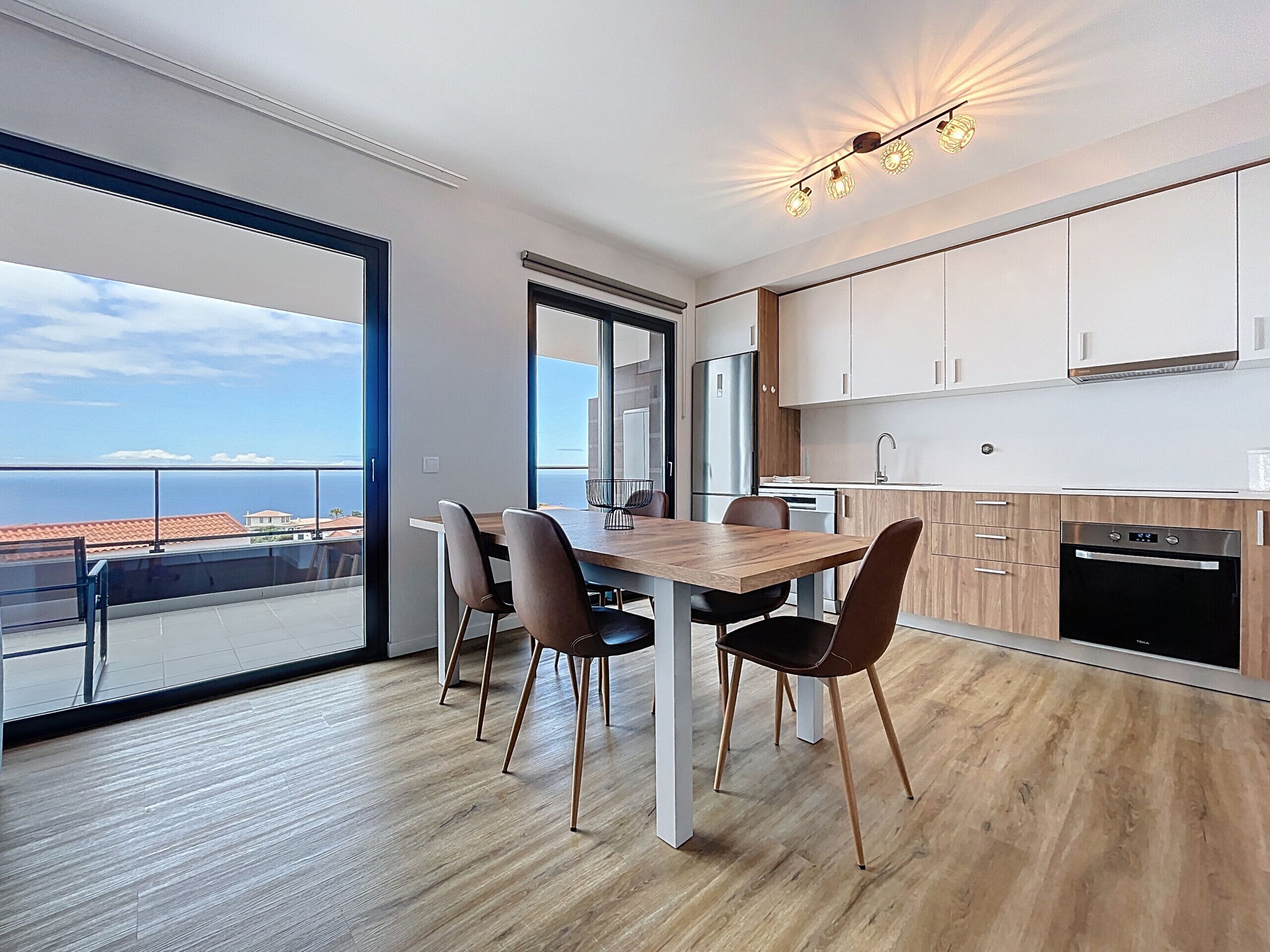 A modern kitchen with wooden cabinets, a stainless steel refrigerator, and a built-in oven.