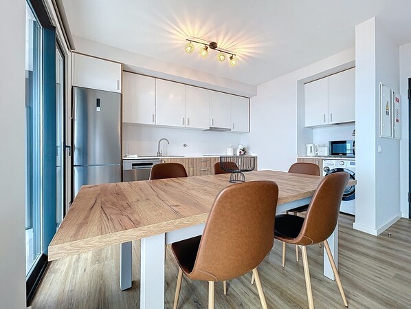 Une cuisine moderne avec une table à manger en bois, quatre chaises et un four encastré.