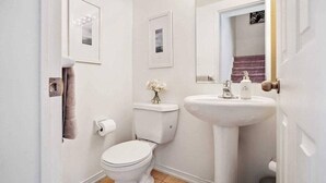 A compact bathroom with a toilet, sink, and framed pictures on the walls. - 2-bedroom plus Den condo in enjoyable Toronto with WiFi, AC (Toronto)